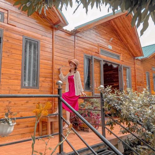 a woman standing on the porch of a wooden house at Cô Tô Homestay 368 in Chung Cap