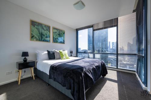 sypialnia z łóżkiem i dużym oknem w obiekcie Mega Style Apartments Mainpoint w Melbourne