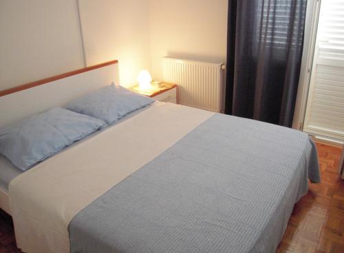 a bedroom with a white bed and a night stand with a lamp at Family friendly house with a swimming pool Jezera, Murter - 5124 in Jezera