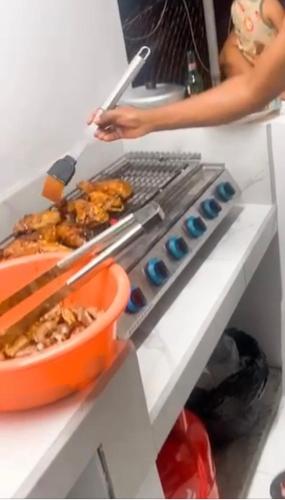 a person cooking food on a grill in a kitchen at HCEAS villa is 5 min fr. airport & to the beaches in Bon Accord