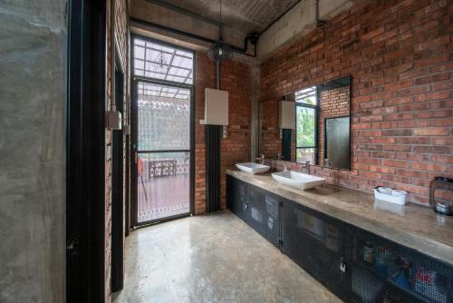 baño con 2 lavabos y pared de ladrillo en Brickhouse Bukit Tinggi by Santai Villas, en Bentong