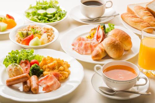 a table with plates of food and cups of coffee at Kusatsu Estopia Hotel in Kusatsu