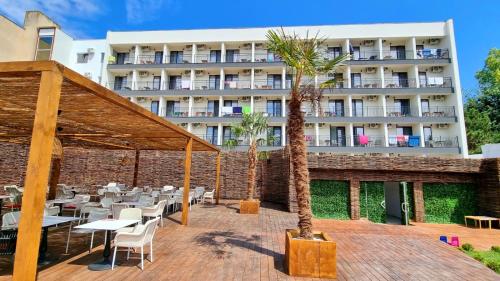 a hotel with tables and chairs and a building at Mojo Resort in Eforie Sud