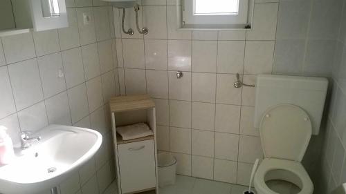 biała łazienka z umywalką, toaletą i umywalką w obiekcie Apartment Jezera 5057g w mieście Jezera