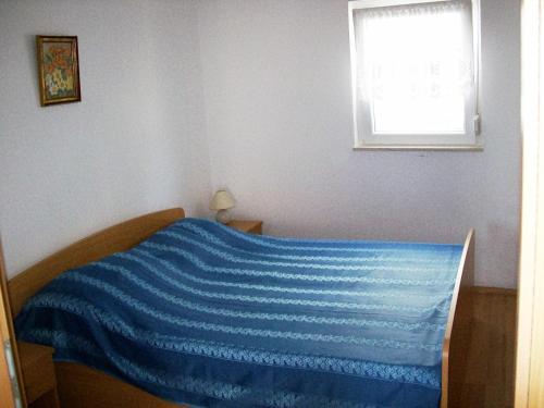 a bedroom with a blue blanket on a bed with a window at Apartment Jezera 5057g in Jezera