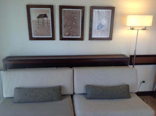 una sala de estar con un sofá y cuadros en la pared en Olas Apart High Comfort en Villa Gesell