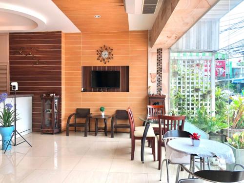 Visanuinn Hotel في ناخون صوان: مطعم به طاولات وكراسي وتلفزيون على الحائط