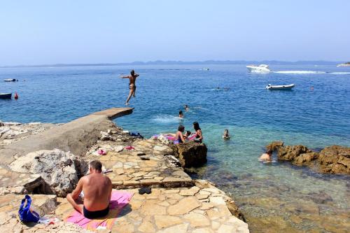 a woman jumping into the water at a beach at Apartments by the sea Zdrelac, Pasman - 15911 in Ždrelac