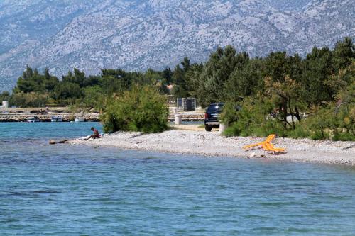 a man sitting on a beach next to the water at Holiday house with a parking space Starigrad, Paklenica - 16126 in Starigrad