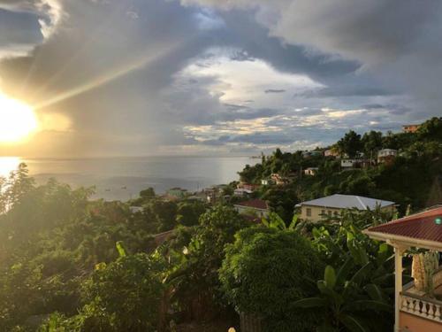 a view of a city with the sun setting over the ocean at Modern Air Conditioned Home For Family & Adventure in Loubiere
