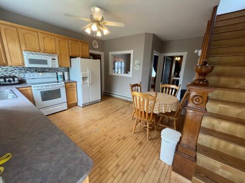 una cocina con electrodomésticos blancos y una mesa con sillas. en The Coastal Country House in New Brunswick, en Cape Tormentine