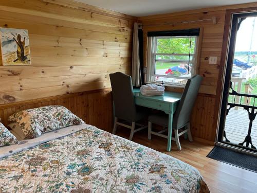 1 dormitorio con cama, escritorio y ventana en The Coastal Cabins in New Brunswick, en Cape Tormentine