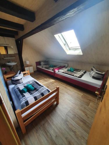 een kamer met 2 bedden op een zolder met een dakraam bij Gästehaus Weißes Lamm - MONTEURZIMMER in Nordhalben