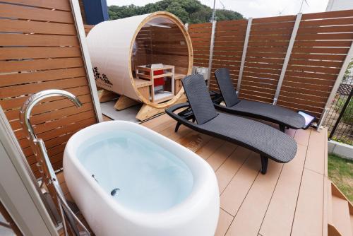 einen Balkon mit einer Badewanne und 2 Stühlen auf einer Terrasse in der Unterkunft しっぽの森リゾート淡路島〜サウナ&スタジオ〜 in Awaji