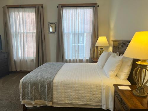 a bedroom with a white bed with two windows at Canyon Rose Suites in Bisbee