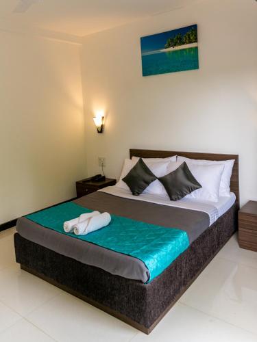 a bedroom with a bed with a towel on it at Aloha Holiday Resort in Baga