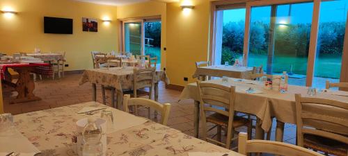 Un restaurante con mesas y sillas y un gran ventanal. en Agriturismo Corte Ambrosi, en Pescantina