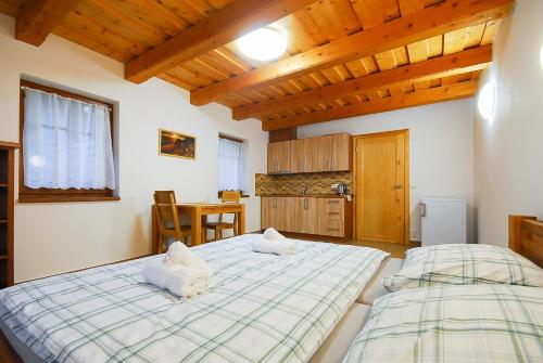 two beds in a room with wooden ceilings at Apartmány Studený in Kunratice