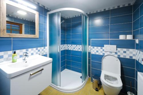 a blue tiled bathroom with a toilet and a sink at Apartmány Studený in Kunratice