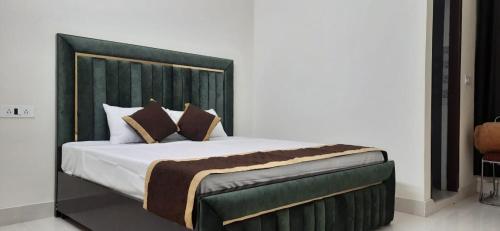 a bedroom with a large bed with a green headboard at Hotel THE BIRD Dehradun in Dehradun