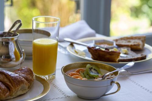 a table with a bowl of soup and a glass of orange juice at Maison de la Garenne & Spa in Vannes