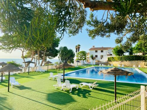 a pool with chairs and umbrellas next to the ocean at La Suite Del Mar in Gran Alacant