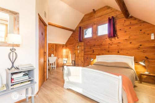 a bedroom with a white bed in a wooden wall at Ferme Cacheterie, boutique terroir in Fleury-la-Forêt