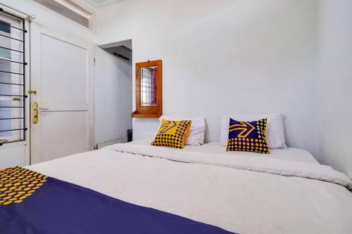 una camera da letto con un grande letto con cuscini gialli e blu di SPOT ON 91386 De Jawara Homestay Syariah a Cilimus 2