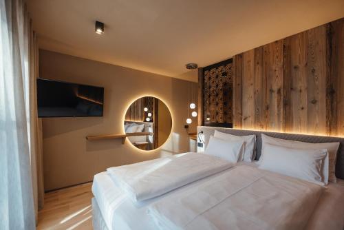 a bedroom with a large white bed and a mirror at Pescosta Chalet Luxury Living in San Vigilio Di Marebbe
