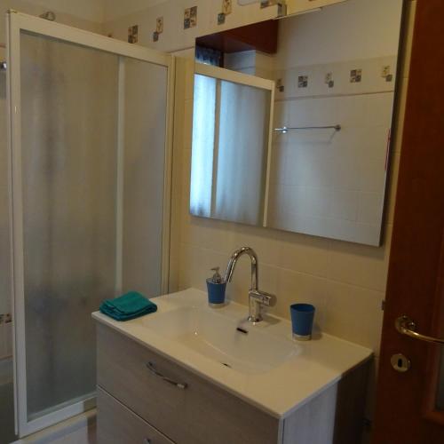 La salle de bains est pourvue d'un lavabo et d'une douche avec un miroir. dans l'établissement Appartamento BLU - Colori del Lago D'Orta - NUOVA STRUTTURA A OMEGNA, à Omegna