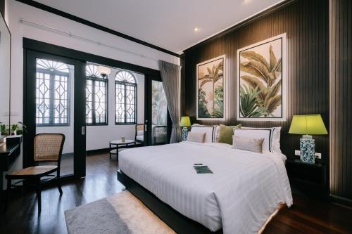 BAAN 125 STAY Phuket في فوكيت تاون: غرفة نوم بسرير ابيض كبير وبعض النوافذ