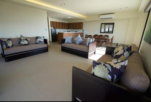 a living room with two couches and a kitchen at Anvaya Cove Short Term Rental Condos in Morong