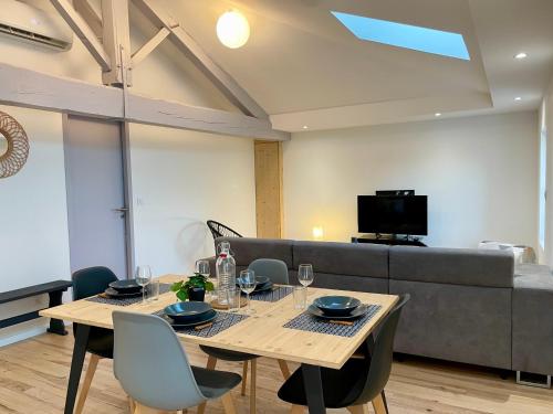 a dining room with a table and a couch at Le Cocon Landais - Clim - Balcon - Central - Spacieux - Lumineux in Mont-de-Marsan