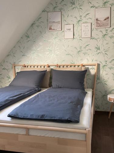 um quarto com uma cama com lençóis azuis e uma parede em FeWo Elbdeichliebe em Boizenburg