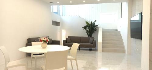 uma sala de estar com uma mesa, uma cadeira e um sofá em Elegant basement Suite em Orosei
