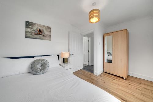 a white bedroom with a bed and a wooden door at Modern Deluxe 5 Bed 3 Bath House London Camberwell Denmark Private Parking in London