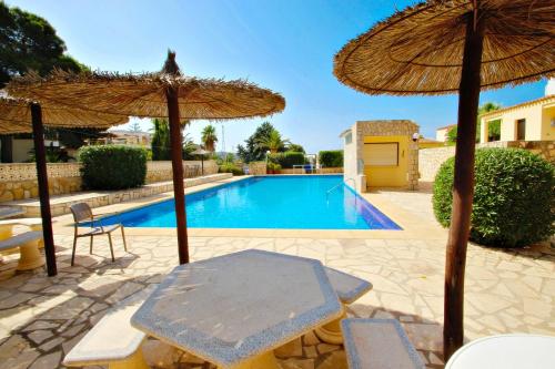 una piscina con sombrilla, mesa y sillas en Magdalena - holiday bungalow with pool in Teulada, en Teulada