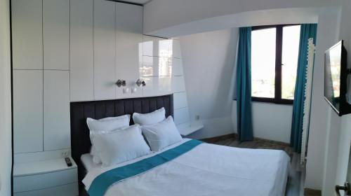 een slaapkamer met een bed met witte lakens en kussens bij Mara Park in Baia Mare