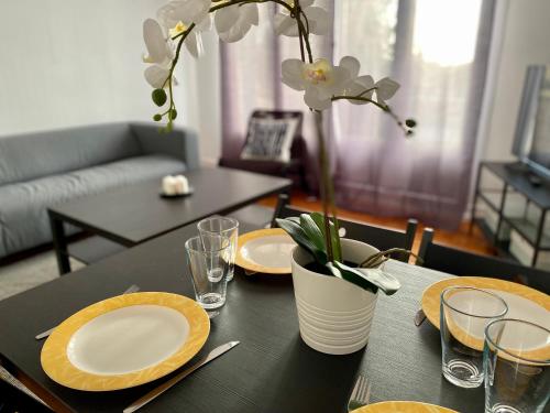 une table avec des assiettes et un vase avec des fleurs. dans l'établissement Appt T4 proche du centre - ville de Rouen - 045, à Rouen