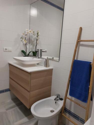 łazienka z umywalką, toaletą i lustrem w obiekcie Precioso apartamento en primera línea de playa de la Barrosa w mieście Chiclana de la Frontera