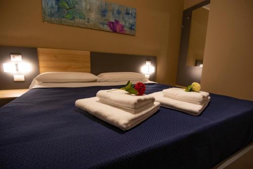 a bedroom with a blue bed with towels on it at ALMA B&B Home Cosenza in Cosenza