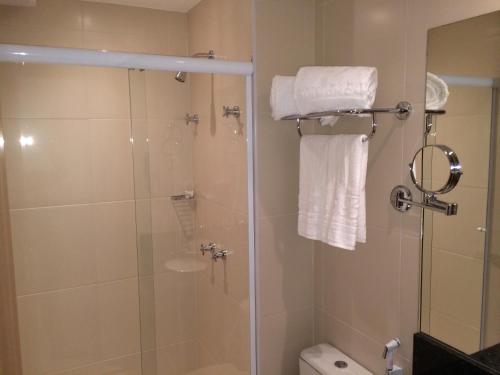 a bathroom with a shower and a toilet and towels at Mont Blanc Diamond Flat in Nova Iguaçu