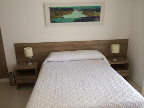 a bedroom with a white bed with two night stands at Hotel Diamond Rede Mont Blanc in Nova Iguaçu