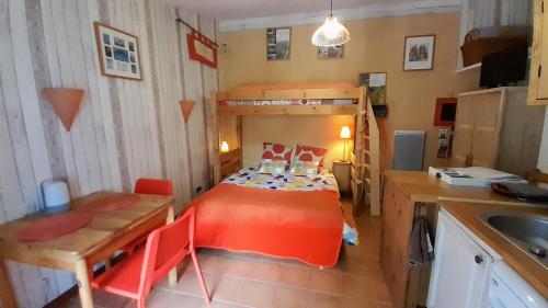 ein kleines Zimmer mit einem Bett und einem Tisch sowie einer Küche in der Unterkunft Gite du figuier in Beaugeay