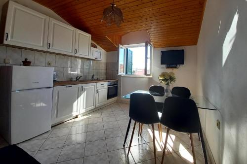 a kitchen with white cabinets and a table and chairs at Apartments with a parking space Grebastica, Sibenik - 4866 in Grebaštica