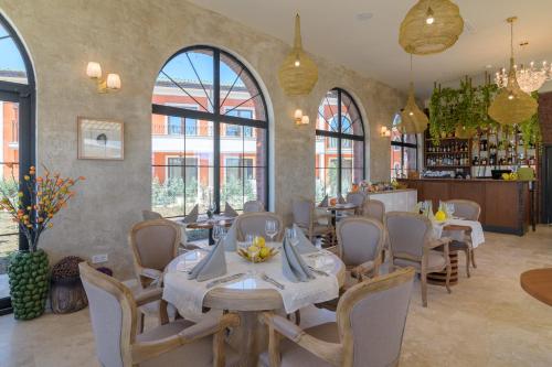 a dining room with tables and chairs and windows at ECO Therma Village - Private Beach & Free Parking in Kranevo