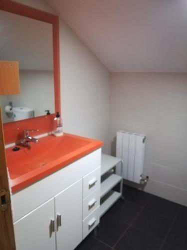 La salle de bains est pourvue d'un lavabo et d'un comptoir rouge. dans l'établissement Habitación grande, à Rasines