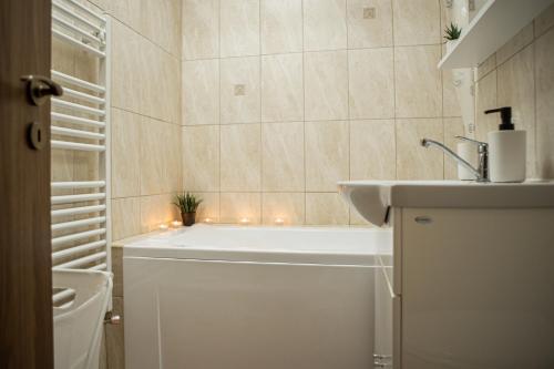ein Bad mit Badewanne, Waschbecken und Beleuchtung in der Unterkunft Henriett’s cosy place in Satu Mare