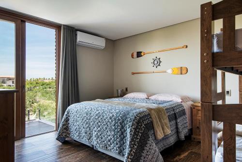 a bedroom with a bed and a large window at 6 suítes com sofisticação e conforto na Praia do Forte! in Praia do Forte