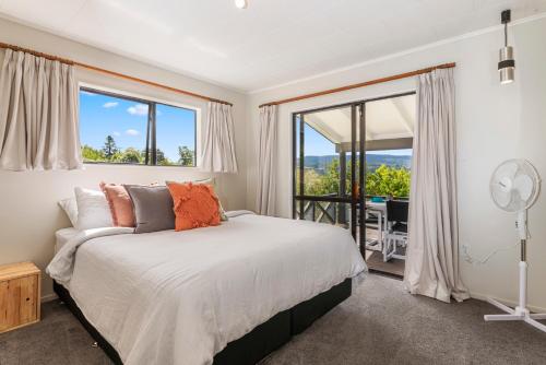 a bedroom with a bed and a large window at Splendour on Spencer - Lake Tarawera Holiday Home in Lake Tarawera